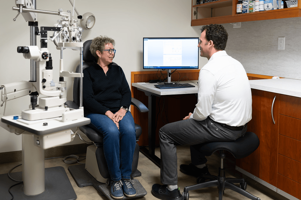 Eye doctor discussing eye exam results with a patient in an optometry exam room.